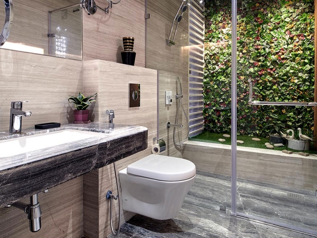 A beautiful bathroom in neutral colours with glass panels and a faux garden arrangement inside the shower cubicle.