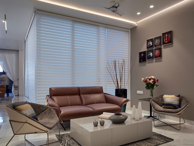 A sitting area in the living room with modern sofas in neutral tones, a minimalistic centre table and personal family photos on the wall.